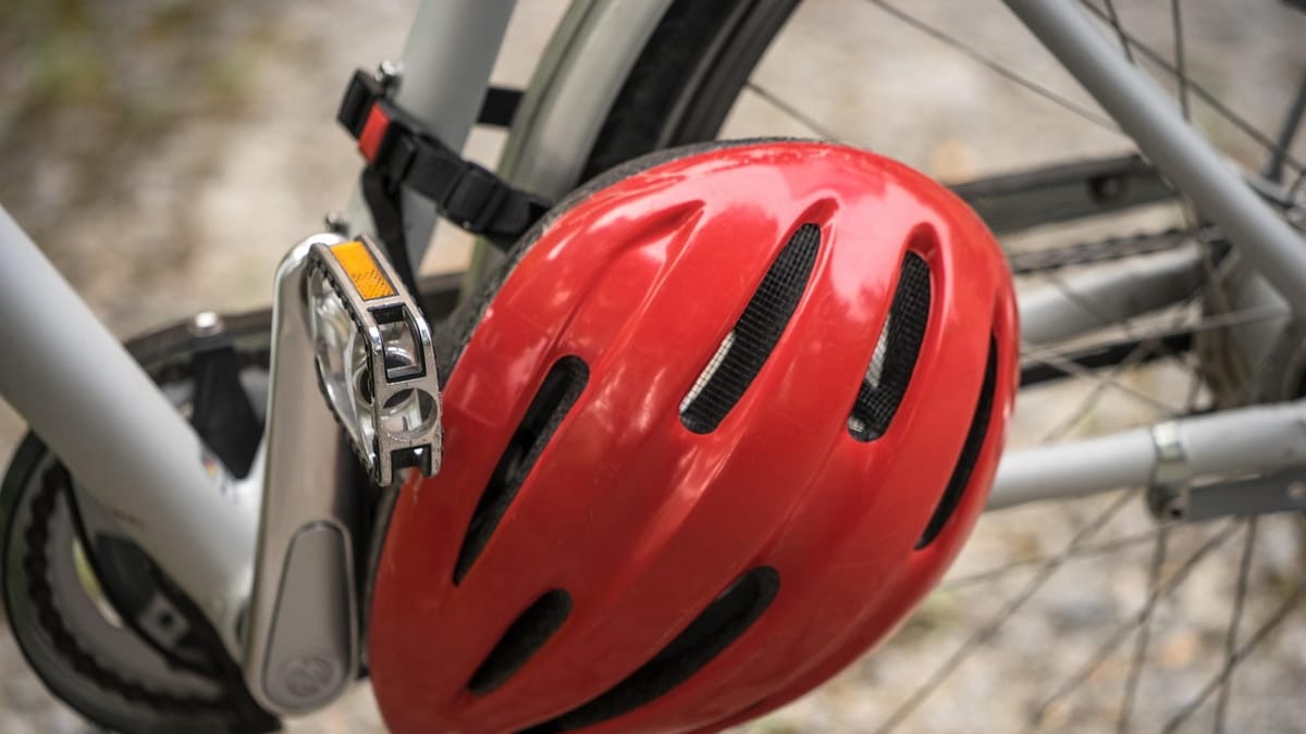 Casque de vélo rouge accroché au cadre d'un vélo à l'arrêt
