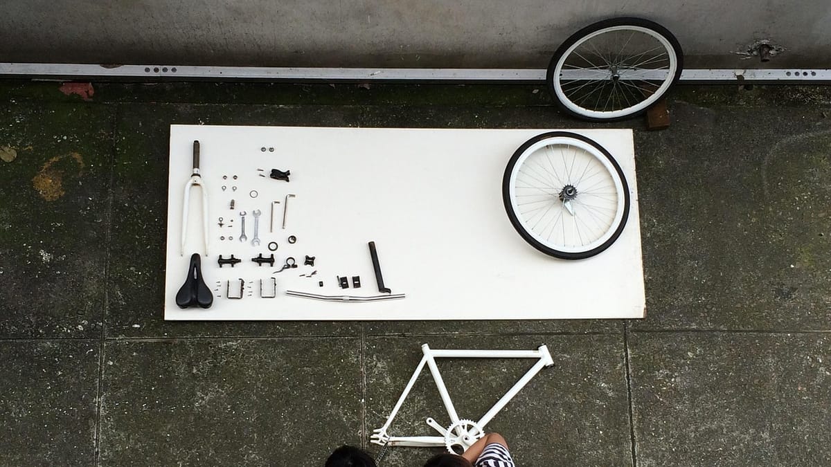 Vélo démonté pièce par pièce sur une planche, vu de dessus, avant remontage