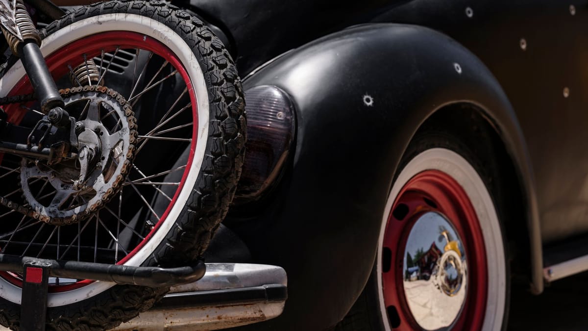 Roue arrière d'un vélo chargé sur un porte-vélos, à l'arrière d'une voiture ancienne