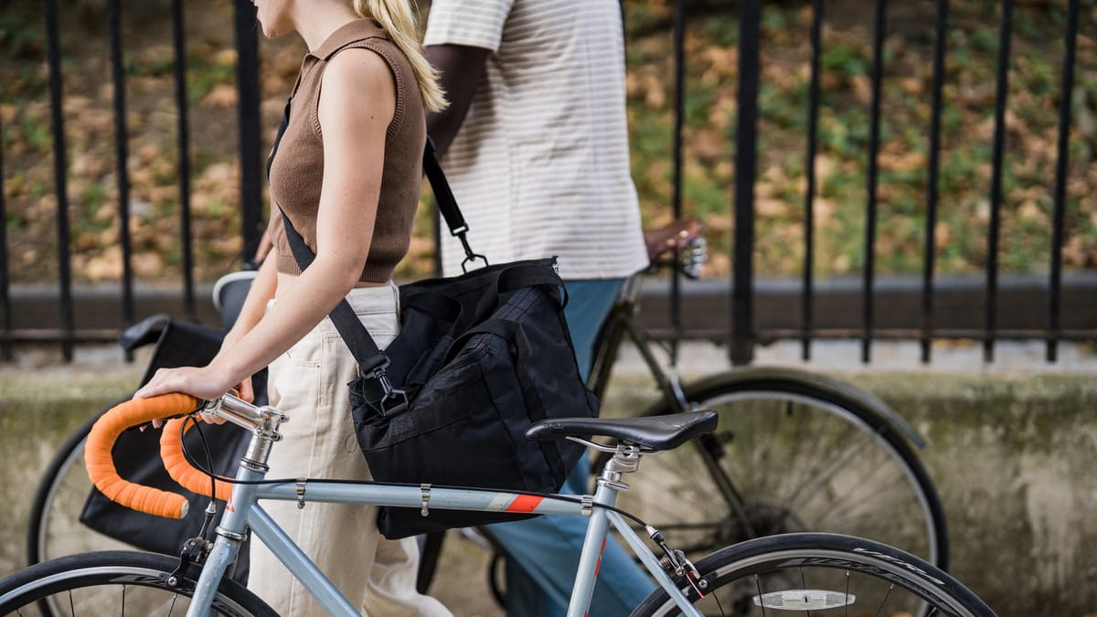 Cycliste poussant son vélo de ville, un grand sac noir porté en bandoulière