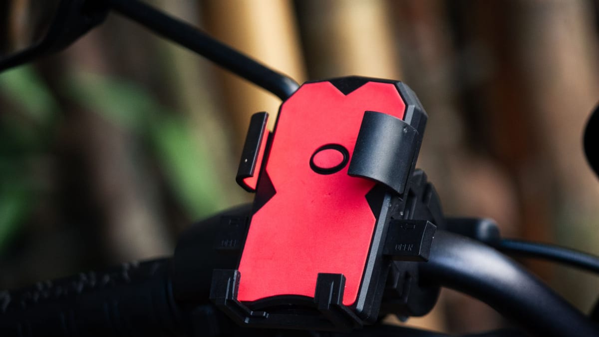Support de téléphone à pince, rouge et noir, fixé sur un guidon de vélo