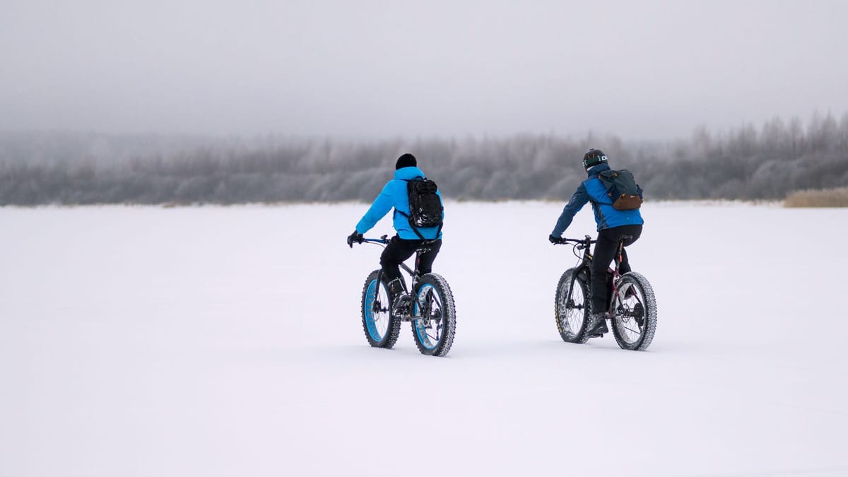 Deux cyclistes sur des fat bikes à pneus larges, sur une étendue enneigée