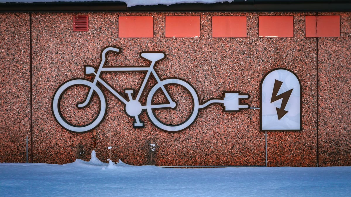 Pictogramme d'un vélo relié à une prise électrique, peint sur le mur d'une borne de recharge